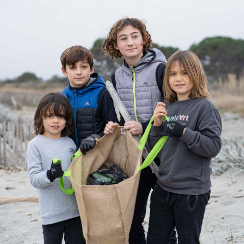 Initiatives Océanes : Un groupe de petits garçons collecte les déchets sur la plage
