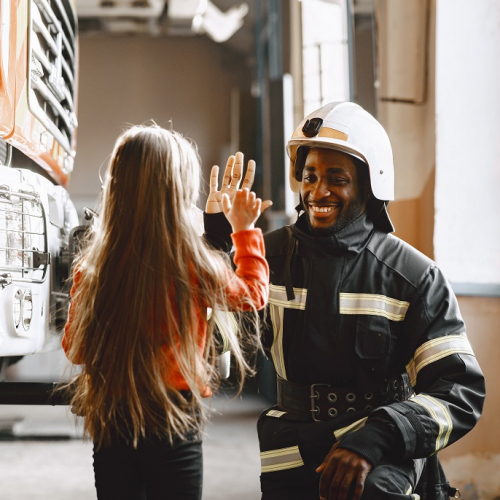 Bals des pompiers : Dans une caserne, une petite fille tape dans la main d'un pompier en uniforme