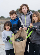 Initiatives Océanes : Un groupe de petits garçons collecte les déchets sur la plage