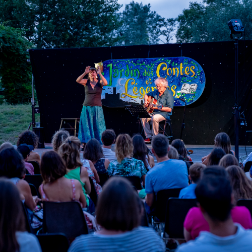 Jardin des Contes et Légendes : Devant une foule, des conteurs sont sur scène à la nuit tombée