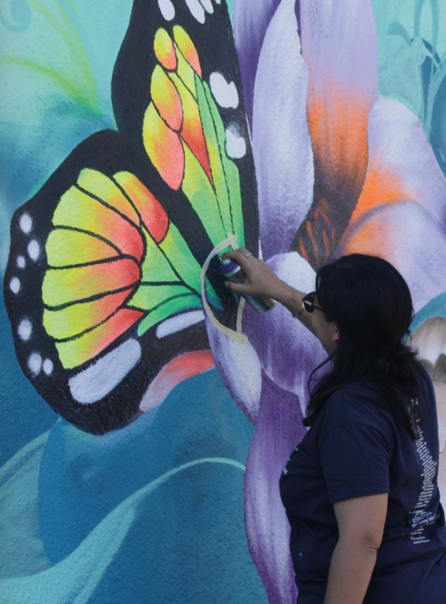 Expo Floya Jam : Une artiste graff un papillon sur un mur