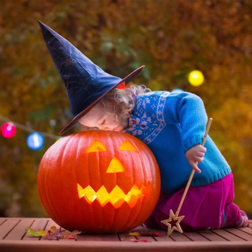 Halloween 2024 à Lyon : Une petite fille déguisée en sorcière ou en fée regarde à l'intérieur d'une citrouille éclairée