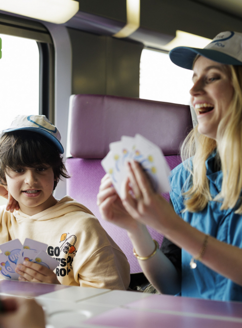 Enfant jouant aux cartes pendant le trajet en train avec Junior & Cie