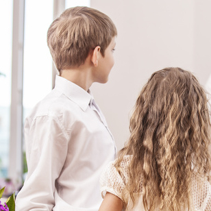 Boy and girl children give flowers as a school teacher