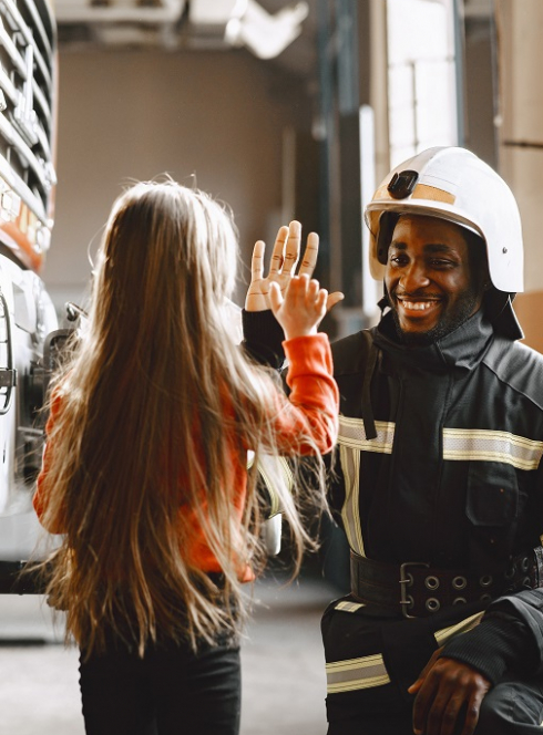 Bals des pompiers : Dans une caserne, une petite fille tape dans la main d'un pompier en uniforme