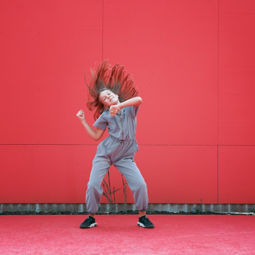 Anou Skan : Une petite fille danse devant un mur entièrement rouge