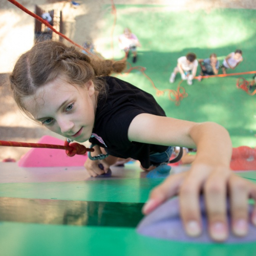 Fille qui grimpe un mur d'escalade
