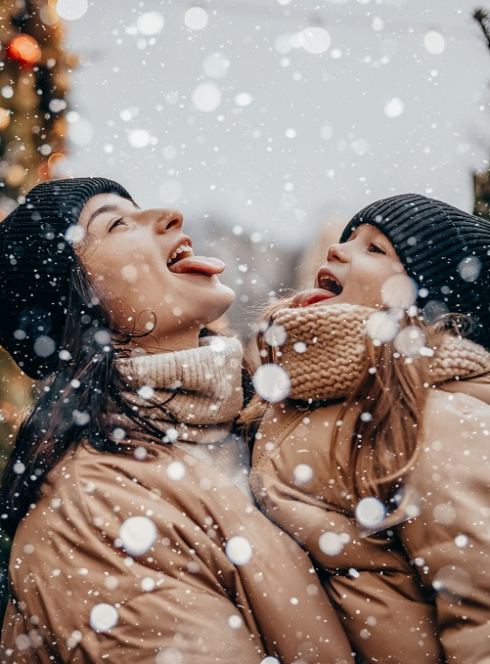 Marchés de Noël 2024 en Rhône-Alpes et à Lyon : Une femme et une petite fille essayent de gober des flocons de neige