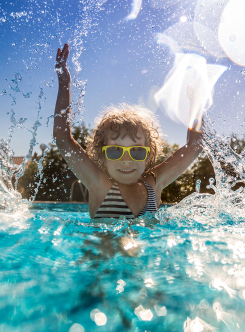 Enfant sautant dans une piscine en été