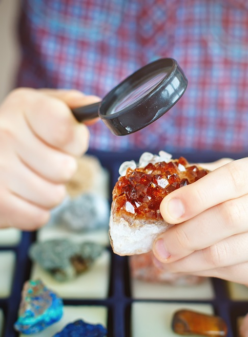 Le salon international des minéraux : Un enfant observe des pierres précieuses à la loupe