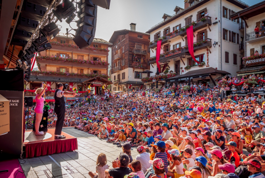Au Bonheur des Mômes : Une grande foule au soleil dans les montagnes devant un spectacle