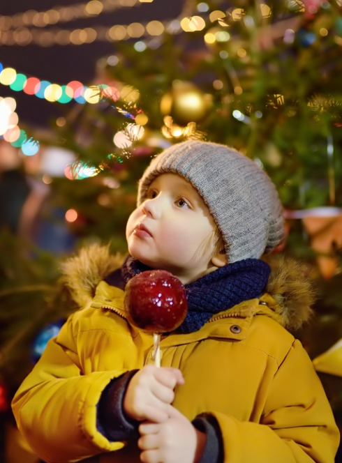 Animations d'hiver à Douai en 2024 : Un petit garçon avec une pomme d'amour au marché de Noël