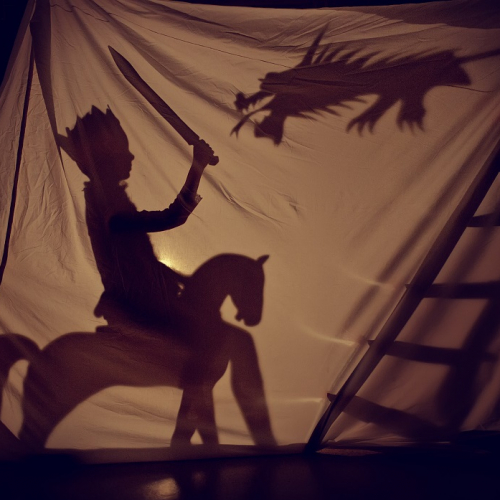 Nuits de la lecture : Un petit garçon déguisé en chevalier en ombre derrière une toile tendue