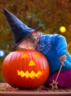 Halloween 2024 à Lyon : Une petite fille déguisée en sorcière ou en fée regarde à l'intérieur d'une citrouille éclairée