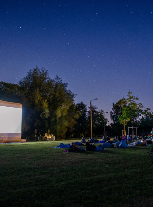 Séances de cinéma plein air à Lille : Des familles couchées dans l'herbe en face d'un écran géant
