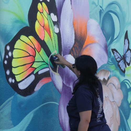 Expo Floya Jam : Une artiste graff un papillon sur un mur