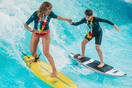 City Surf Park : Une monitrice et un jeune garçon surfent