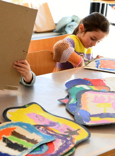 Les ateliers des vacances au LAAC : Une petite fille découpe du carton peint