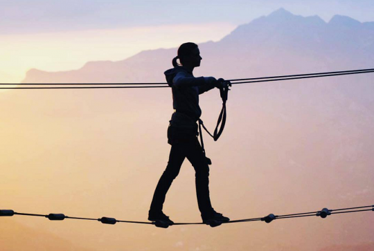 Peira Cava Aventures : Une jeune fille traverse un pont en hauteur au coucher du soleil