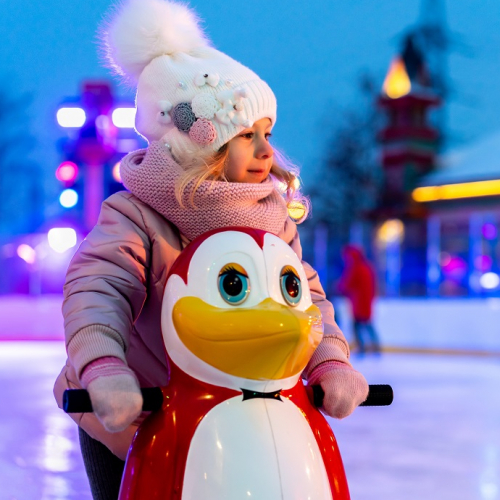Patinoires : Une petite fille s'amuse sur la glace avec un pingouins pour l'aider