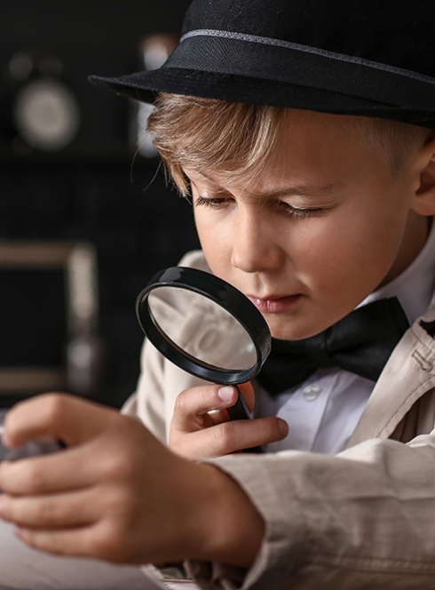 John Doe Escape Game France : Un petit garçon déguisé en enquêteur avec une loupe