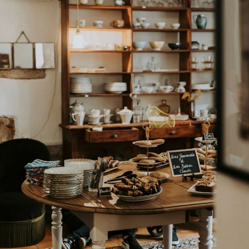 BrocCafé : Une table avec des gâteaux dessus au milieu d'objets de brocante
