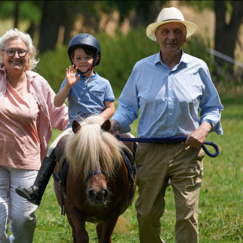 La journée du cheval : Petit garçon sur un poney entouré de ses grands parents
