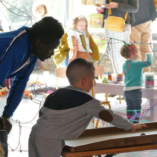 Maison Folie : Petit garçon joue à un jeu accompagné d'un adulte