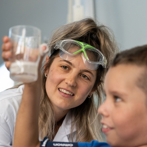 Fête de la science : Une scientifique avec un enfant observent un petit bocal