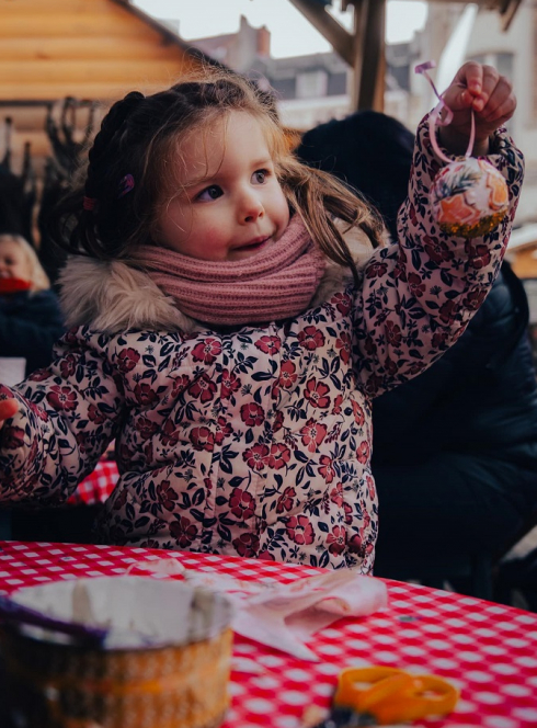 Marché de Noël de Lille et du Nord en 2024 : Une petite fille au marché de Noël tient une boule à accrocher au sapin
