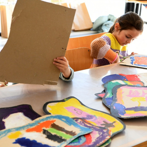 Les ateliers des vacances au LAAC : Une petite fille découpe du carton peint