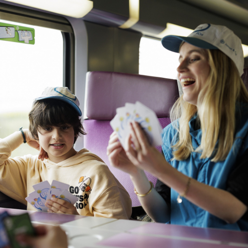 Enfant jouant aux cartes pendant le trajet en train avec Junior & Cie