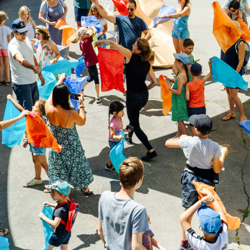 Ideklic : Des enfants et des parents agitent des foulards colorés