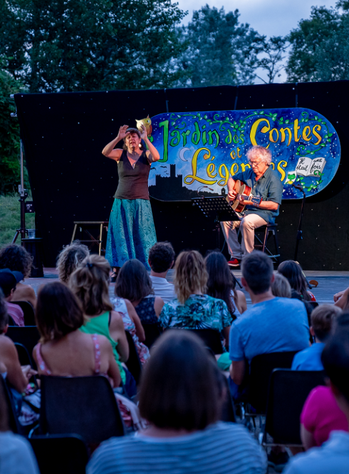 Jardin des Contes et Légendes : Devant une foule, des conteurs sont sur scène à la nuit tombée