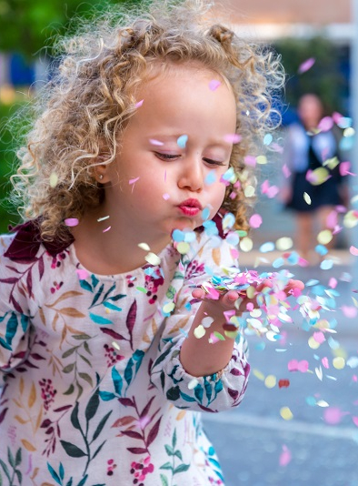 Adobe Stock - petite fille qui souffle sur des confettis