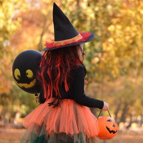Le Pays d'Issoire organise Halloween : Une petite fille déguisée en sorcière au milieu d'arbres aux couleurs d'automne