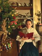 Noël d'antan au Musée de la Vie Rurale : Une dame en costumé d'époque fait la lecture à côté d'un sapin de Noël