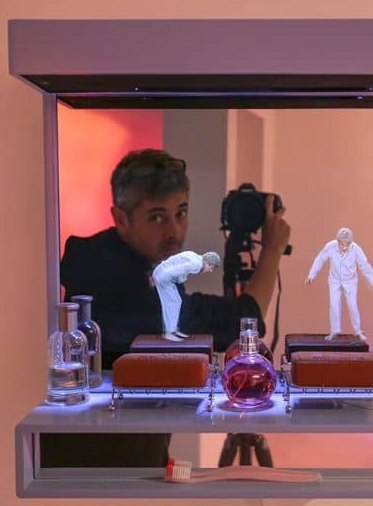 Expo Faire bonne(s) figure(s) : L'artiste devant une installation avec un appareil photo