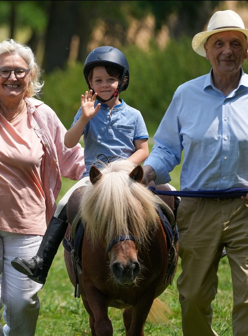 La journée du cheval : Petit garçon sur un poney entouré de ses grands parents