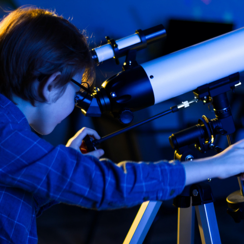 Nuit des Étoiles : Un petit garçon observe le ciel avec un instrument optique