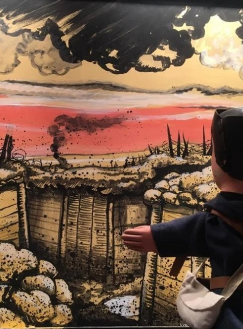 L'armistice selon Guignol : Guignol devant une peinture qui représente les tranchées