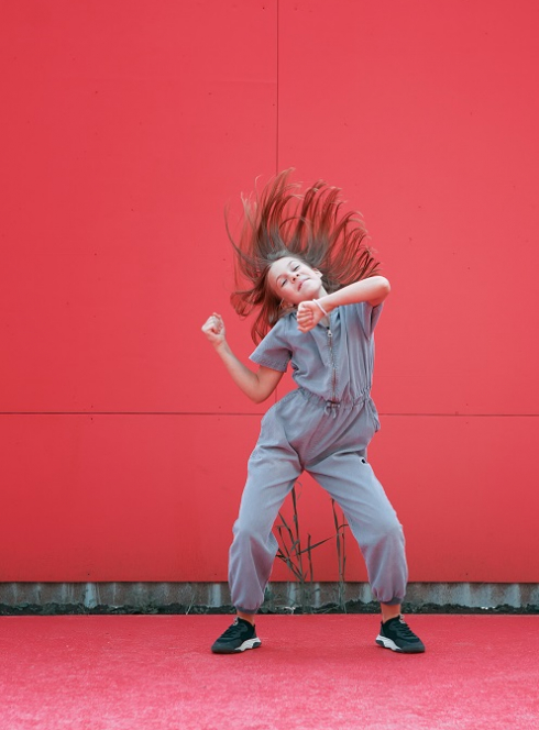 Anou Skan : Une petite fille danse devant un mur entièrement rouge