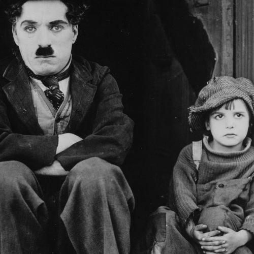 Expo The Kid : Image du film avec Charlie Chaplin assis à côté d'un enfant
