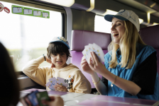Enfant jouant aux cartes pendant le trajet en train avec Junior & Cie