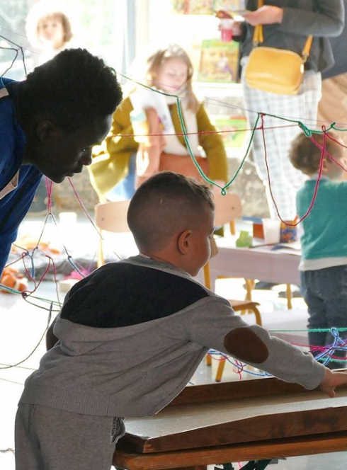 Maison Folie : Petit garçon joue à un jeu accompagné d'un adulte