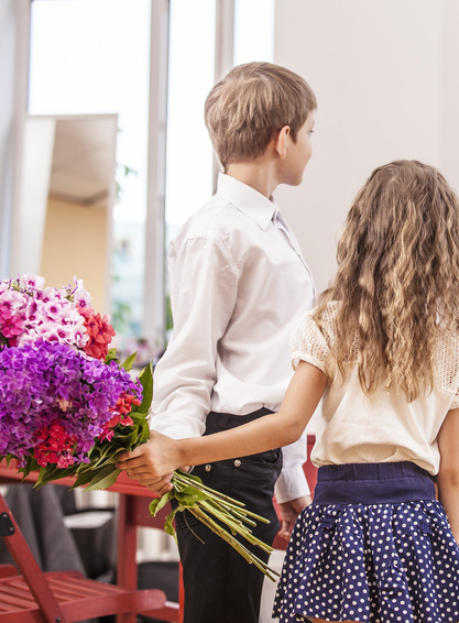 Boy and girl children give flowers as a school teacher