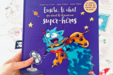 Une main montre le livre "Eusèbe, le chat qui rêvait de devenir un super-héros"