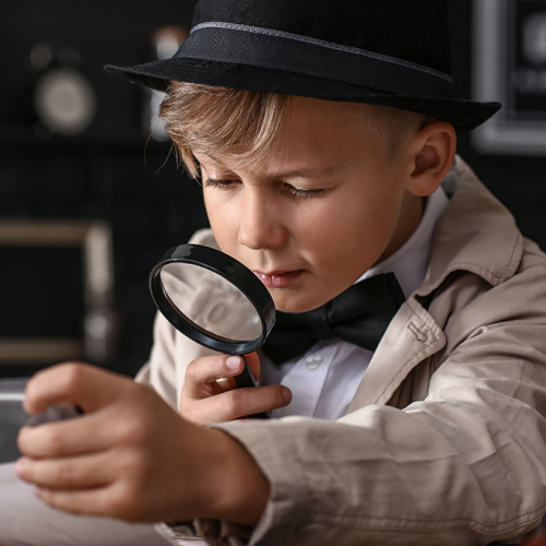 John Doe Escape Game France : Un petit garçon déguisé en enquêteur avec une loupe