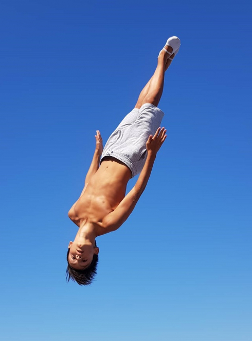 Kelotrampo : Un jeune garçon saute en l'air, figure acrobatique sur trampoline