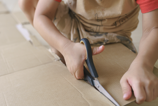 Enfant qui découpe du carton avec un ciseau